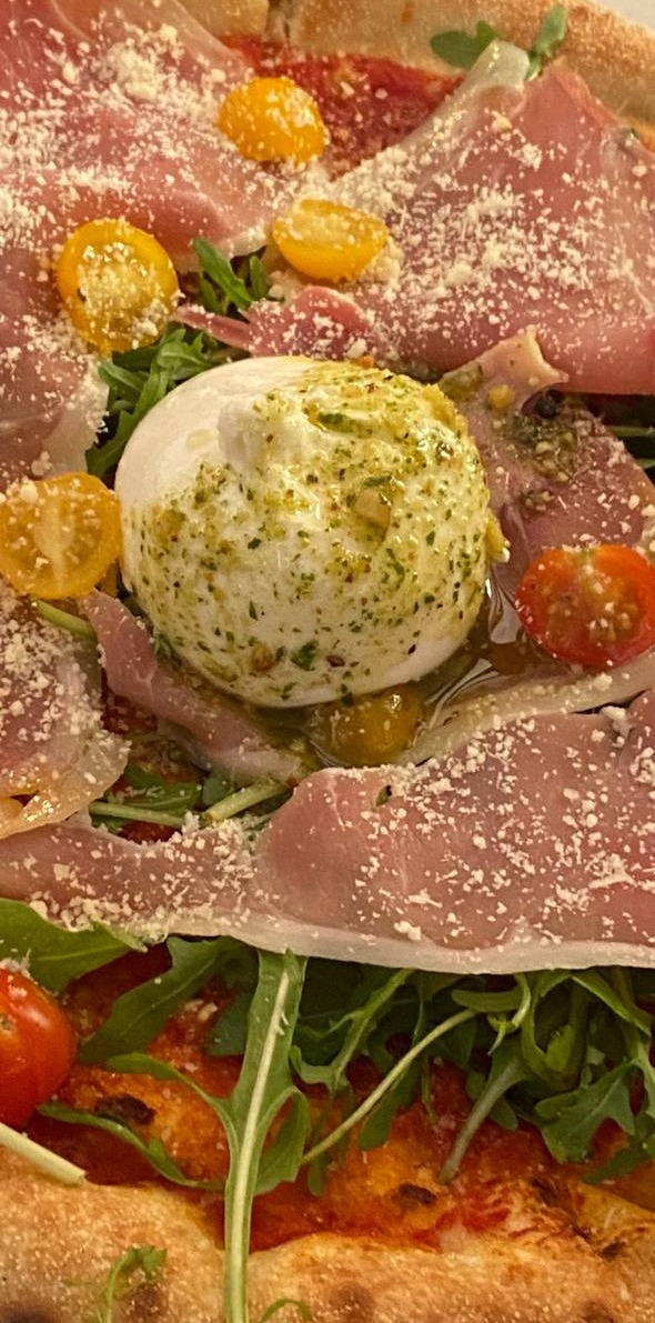 Burrata au pistou au centre d'une pizza au prosciutto